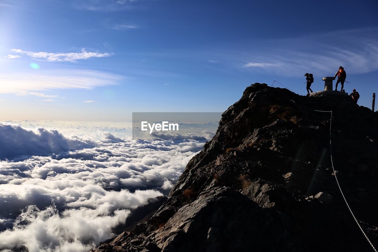 PEOPLE ON MOUNTAIN AGAINST SKY