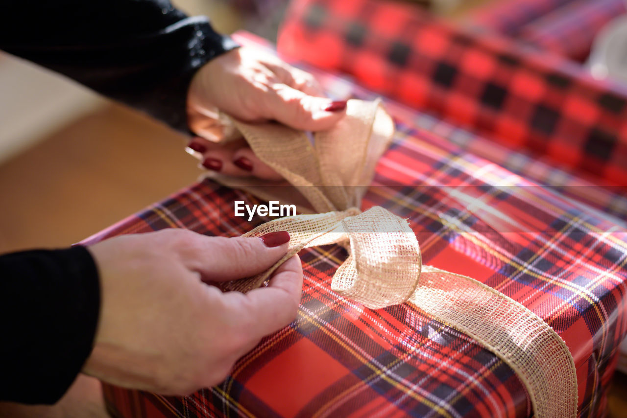 Cropped hands of woman wrapping gift at home