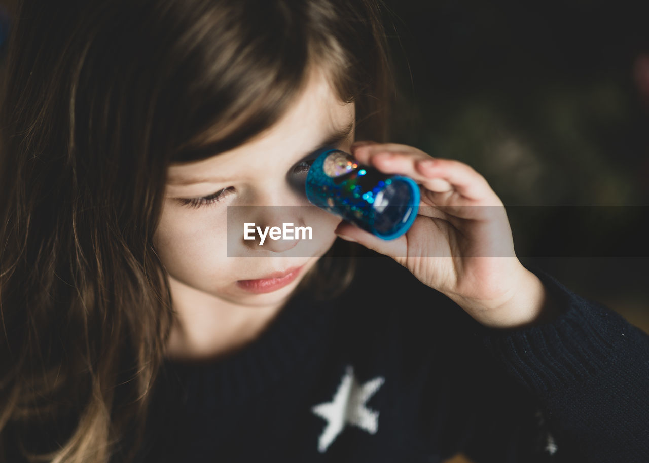 Close-up of girl looking through kaleidoscope toy