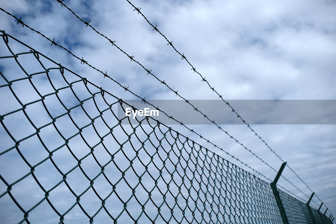 Low angle view of chainlink fence against sky