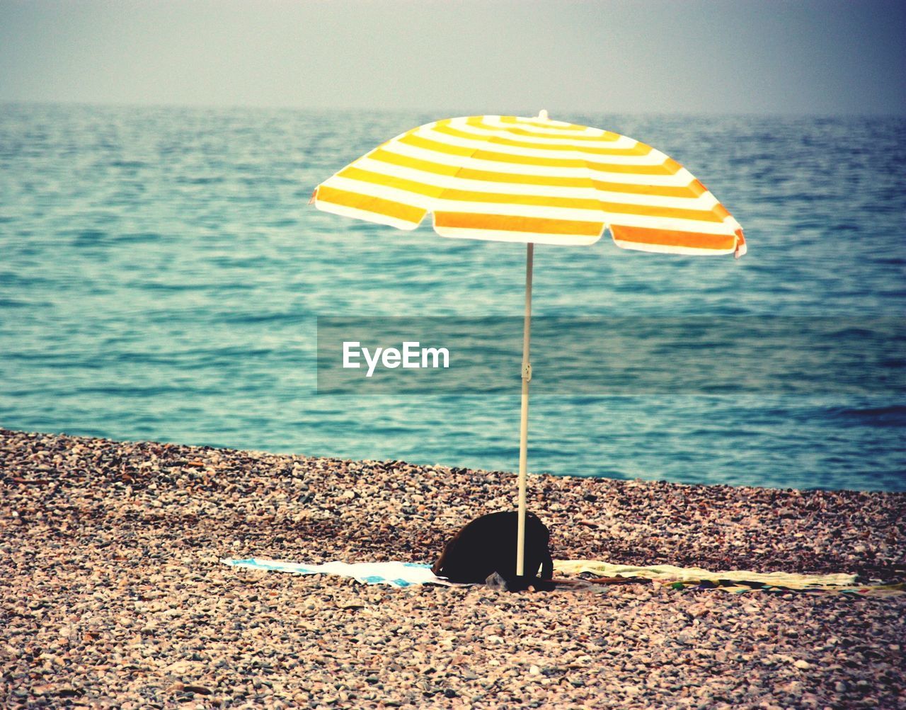 CLOSE-UP OF YELLOW PARASOL ON BEACH