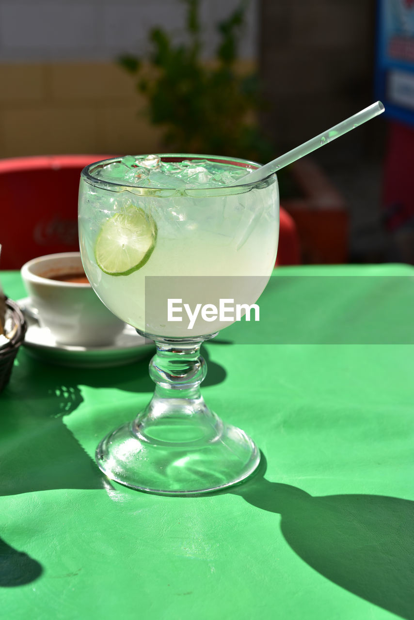 Large glass of lemonade with lime slice in glass and plastic straw, served in mexican restaurant 