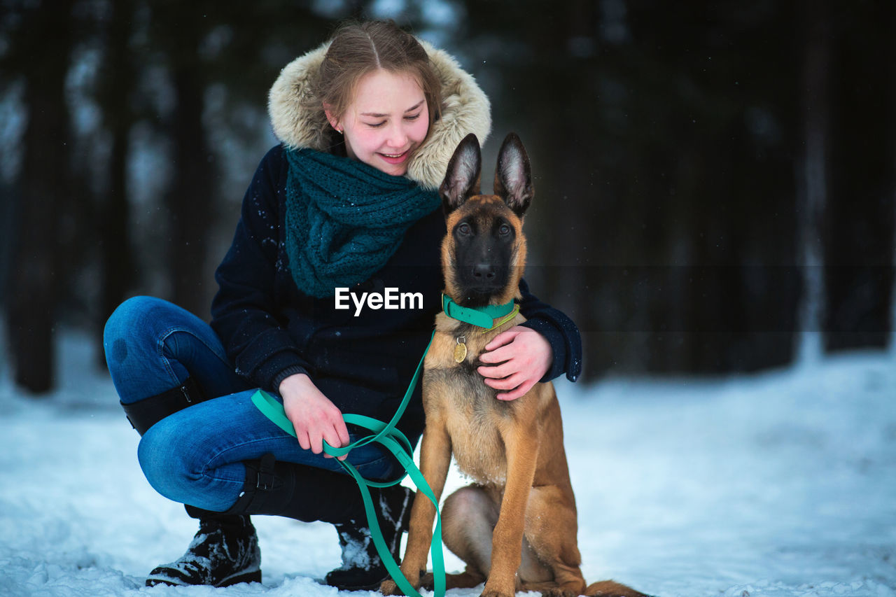 WOMAN WITH DOG SITTING ON SNOW