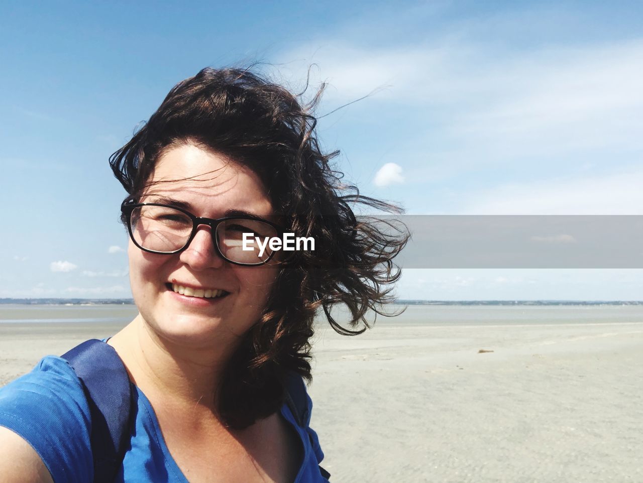 Portrait of smiling woman at beach against sky