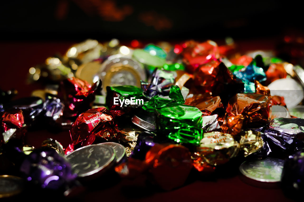 Close-up of colorful wrapped chocolates with coins on table