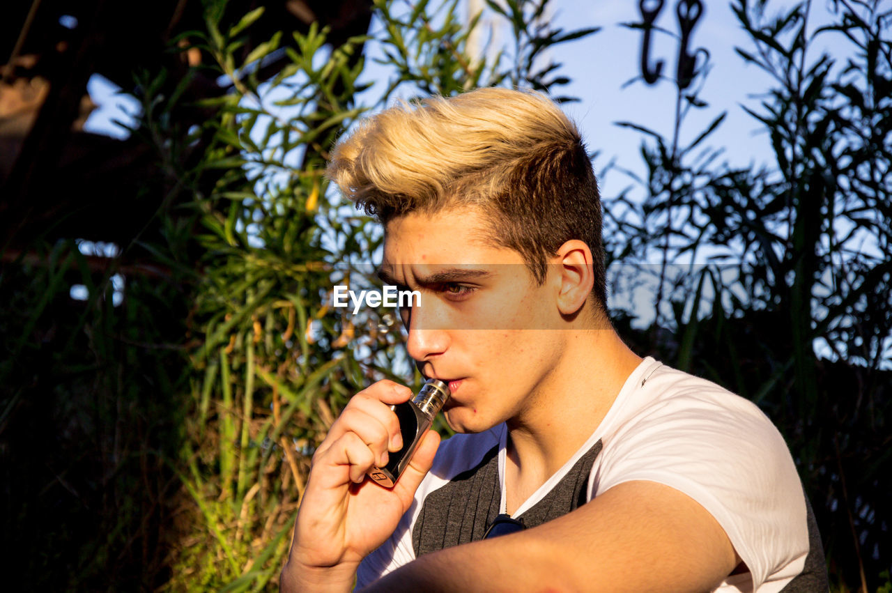 PORTRAIT OF YOUNG MAN LOOKING AWAY OUTDOORS