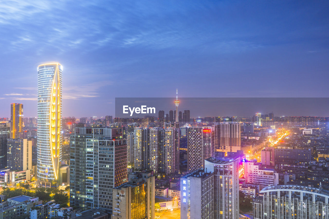 Illuminated buildings in city against sky