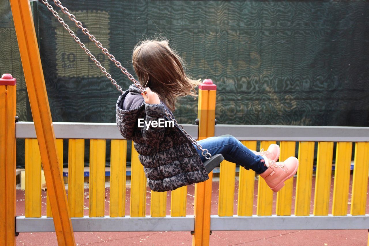 Girl playing on swing at playground