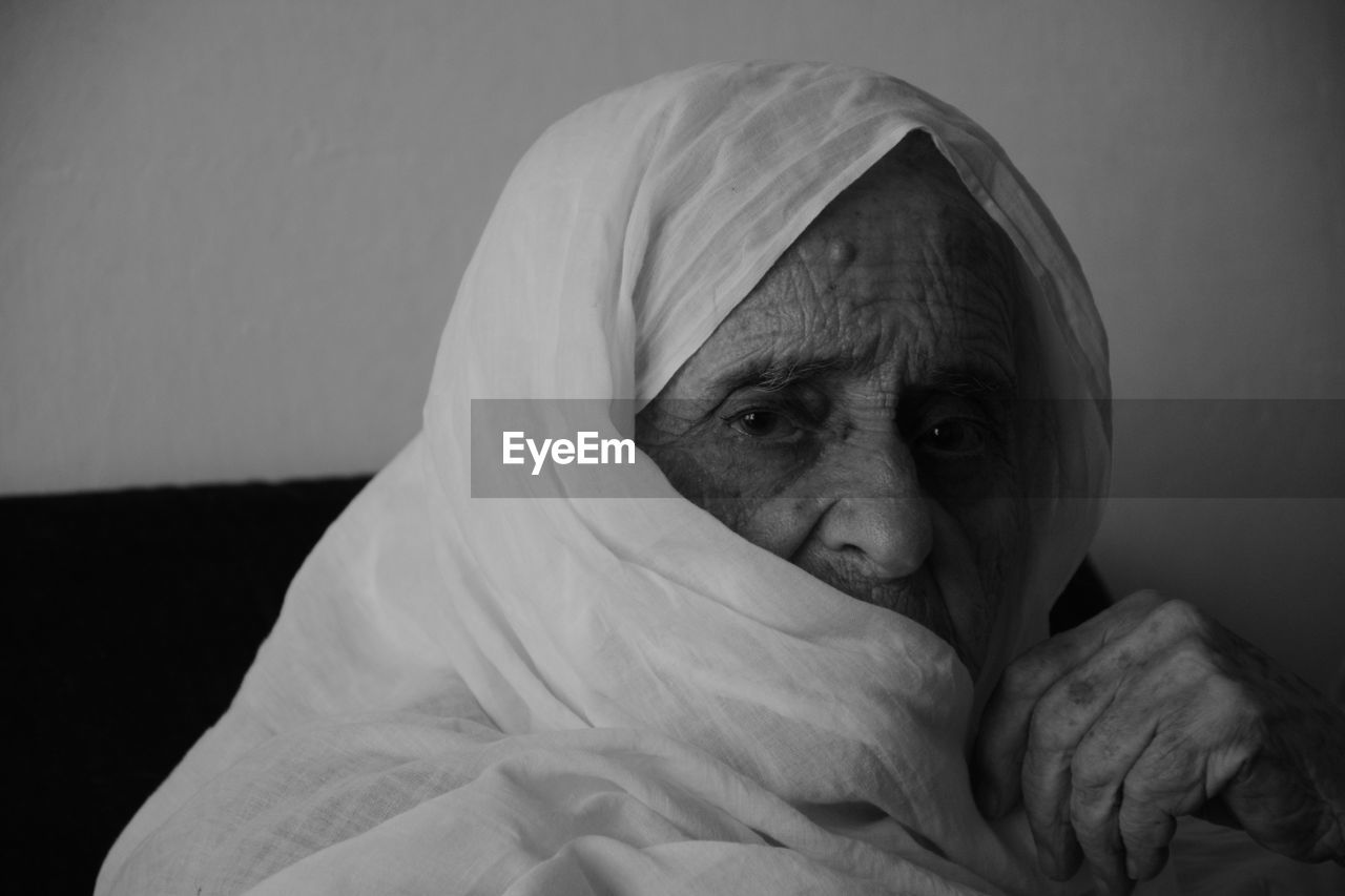 Close-up portrait of senior woman in sari relaxing while sitting on sofa at home