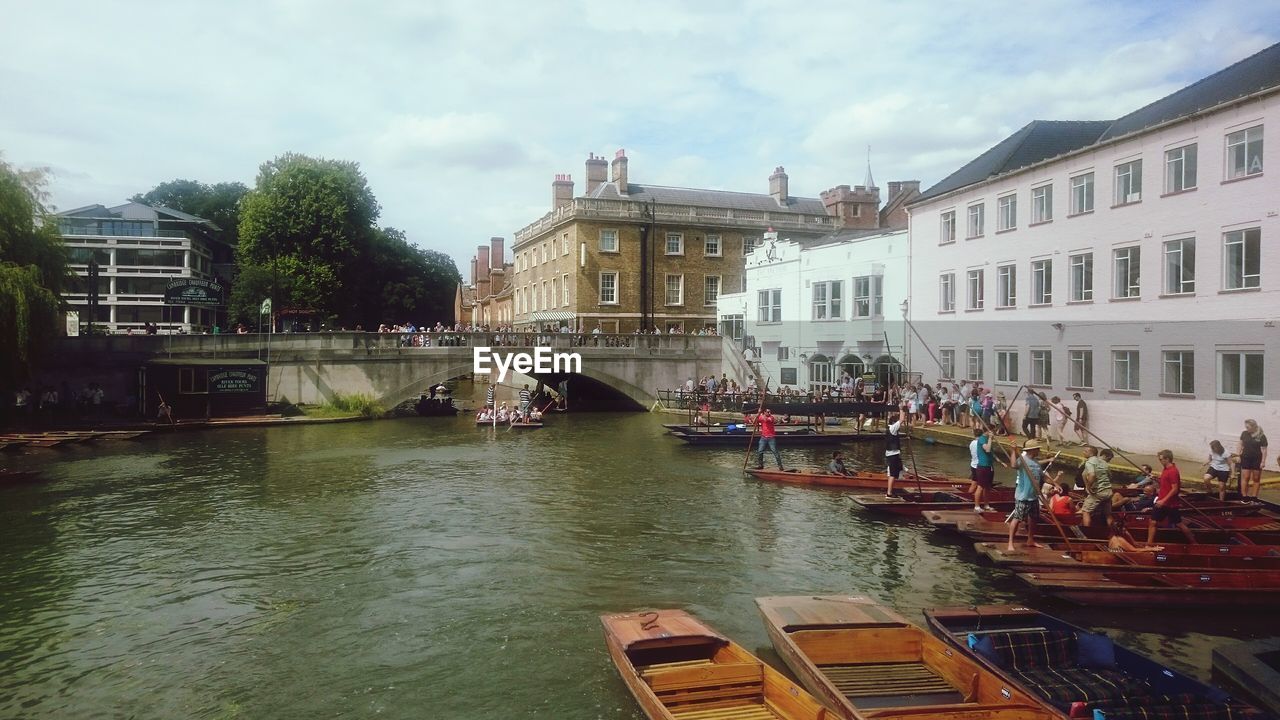 People on traditional boats at river by buildings