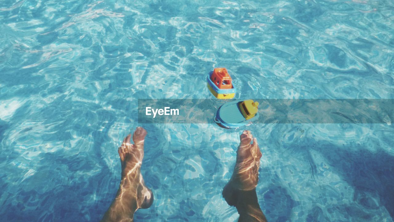 HIGH ANGLE VIEW OF TOY FLOATING ON SWIMMING POOL