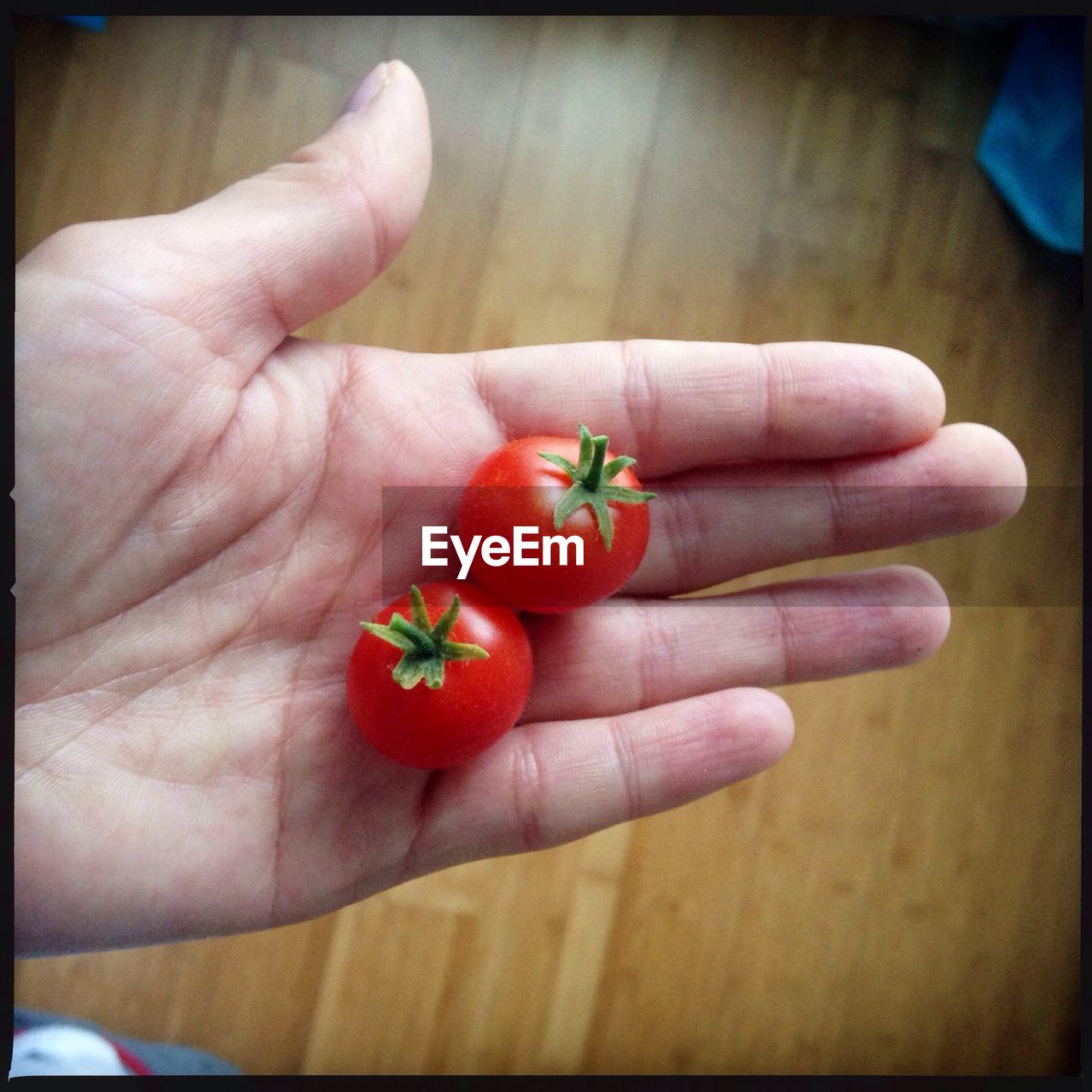 Man holding two cherry tomatoes