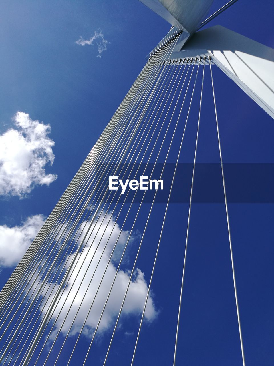 LOW ANGLE VIEW OF SUSPENSION BRIDGE CABLES AGAINST CLOUDY SKY