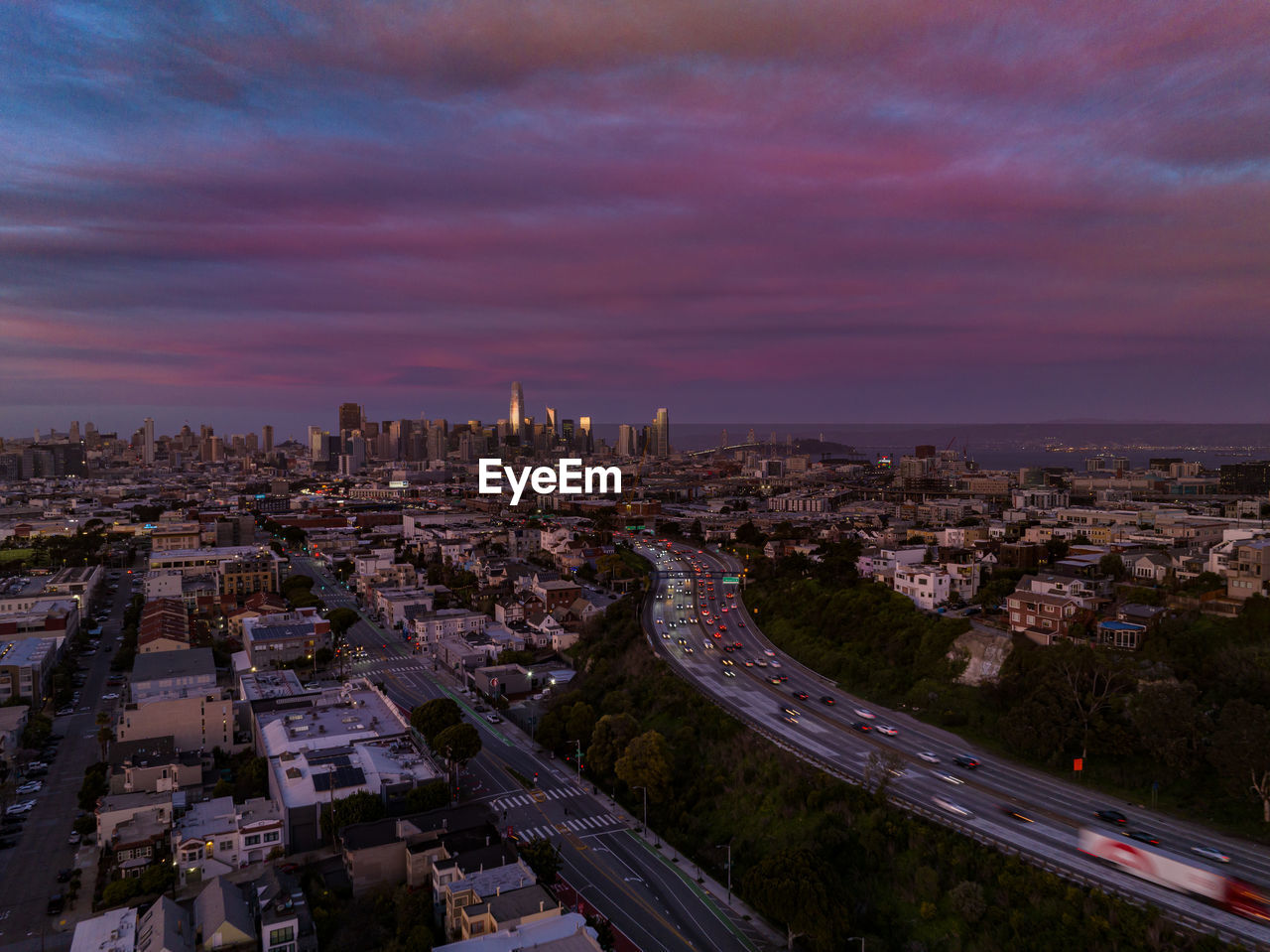 Heavy traffic on multilane motorway at dusk. cityscape with colourful clouds in sky and downtown