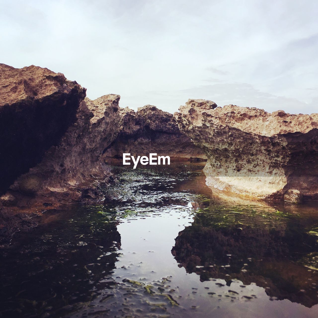 Rock formations in water against sky