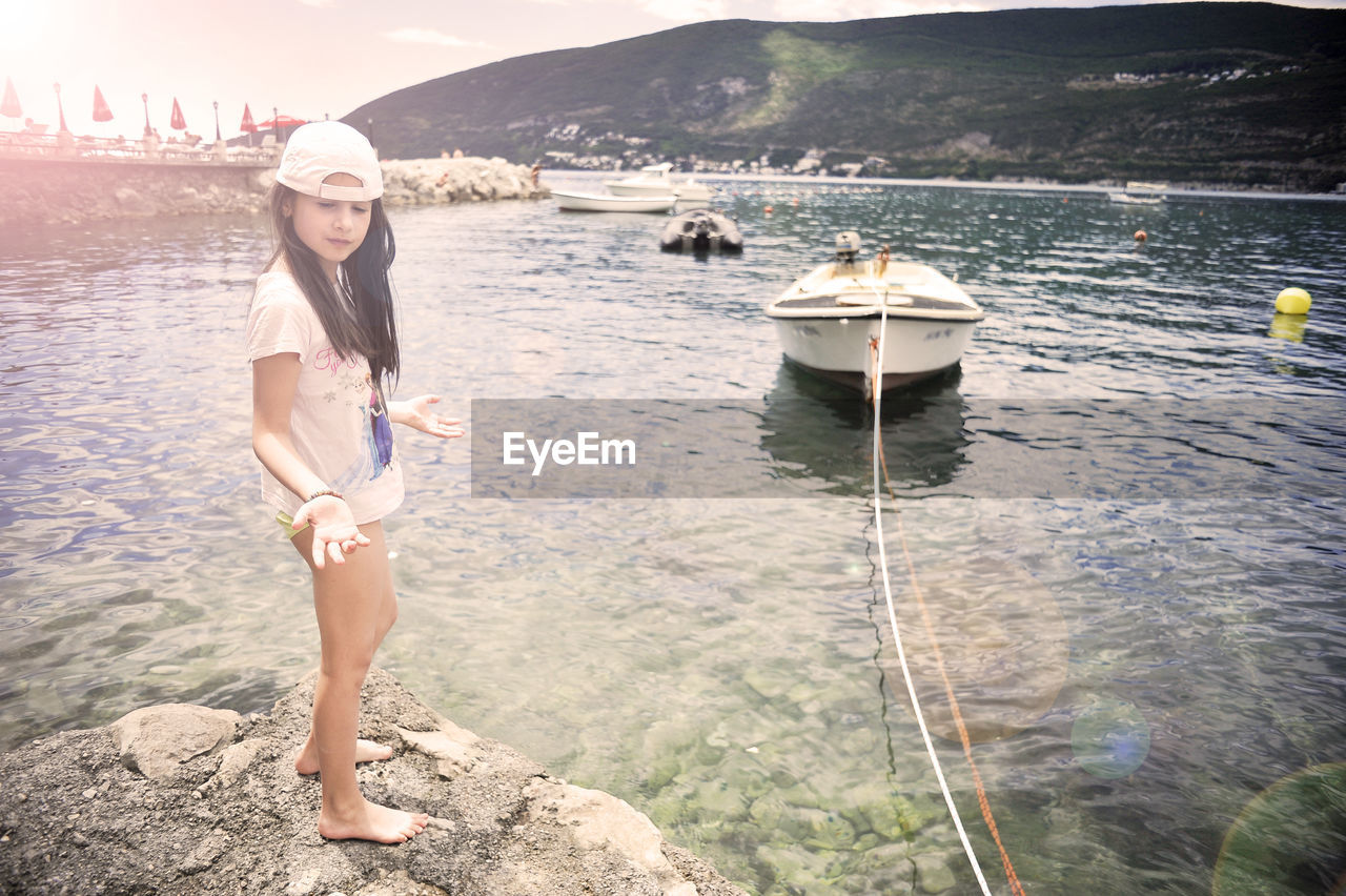 PORTRAIT OF YOUNG WOMAN STANDING ON SEA