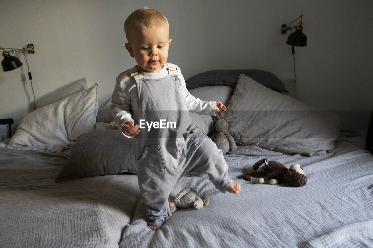 Baby boy walking on bed barefoot