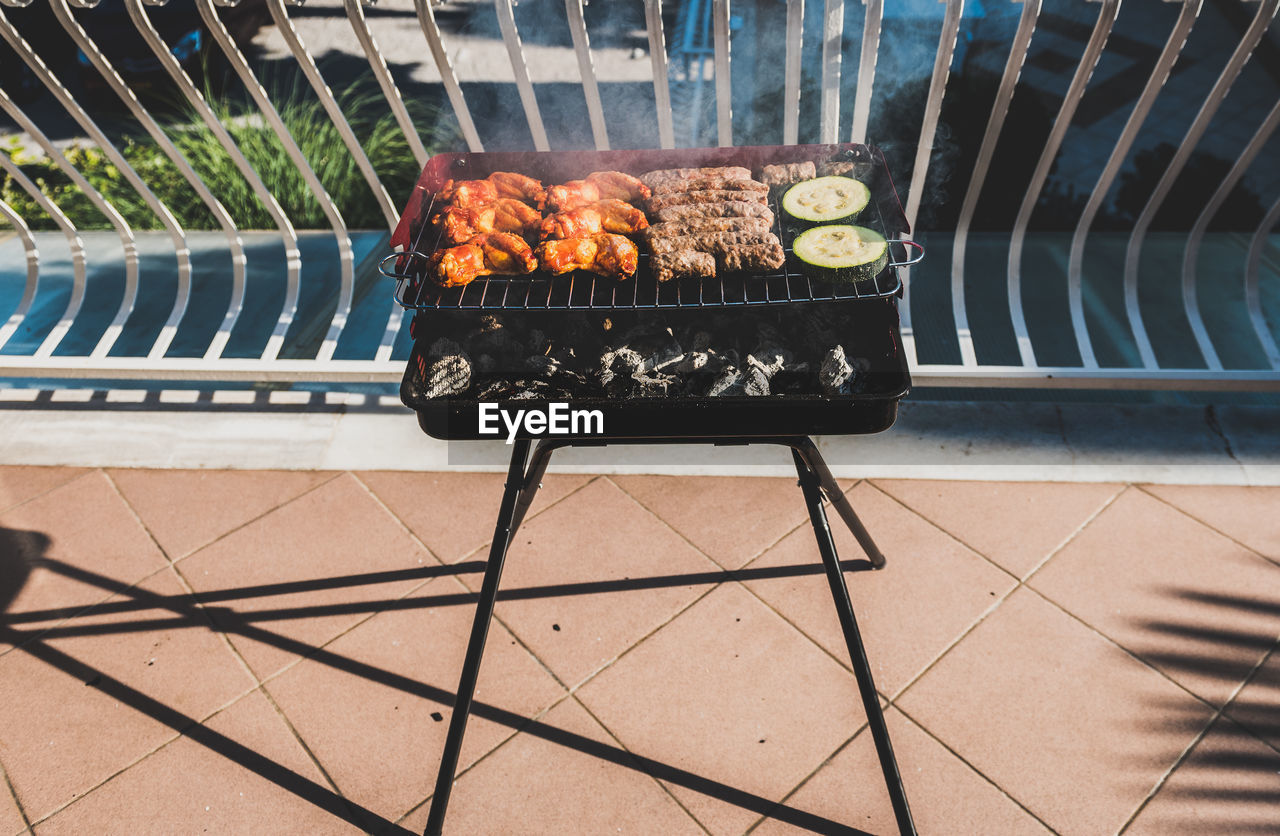 High angle view of meat on barbecue grill at balcony