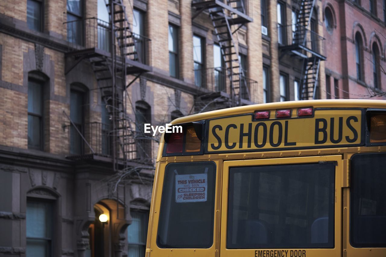 Traditional yellow school bus driving along street in new york city on cloudy day