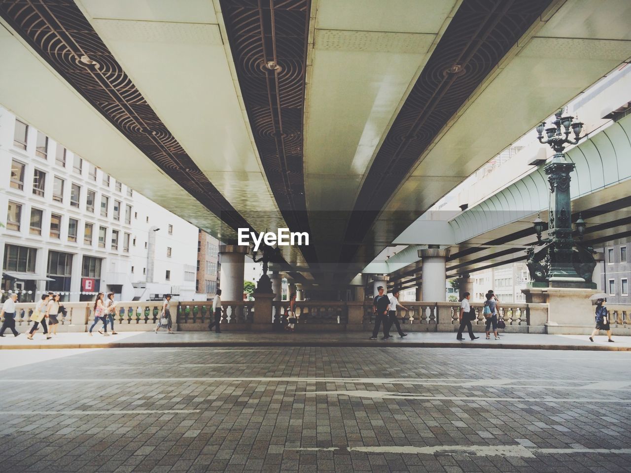 People walking on sidewalk under bridge