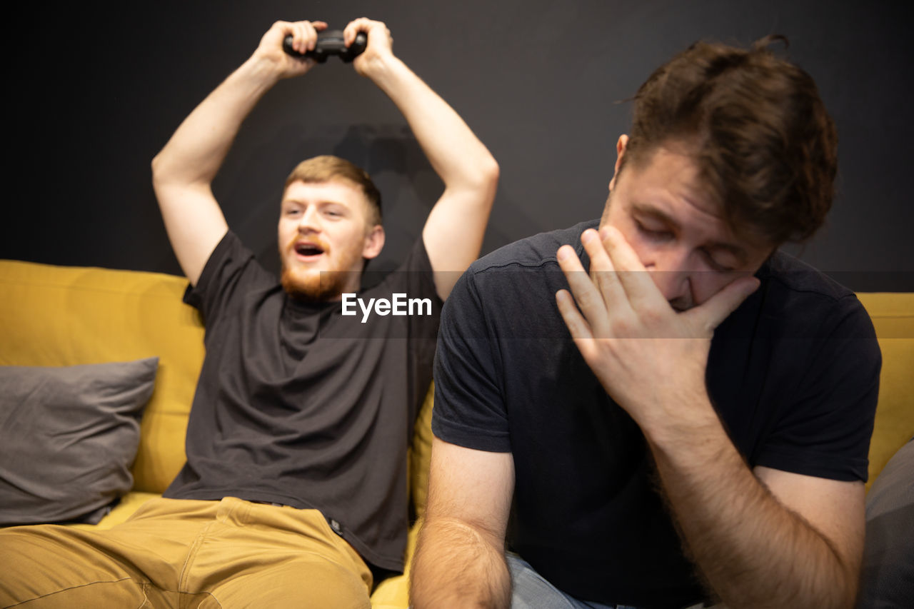PORTRAIT OF A YOUNG COUPLE SITTING ON SOFA