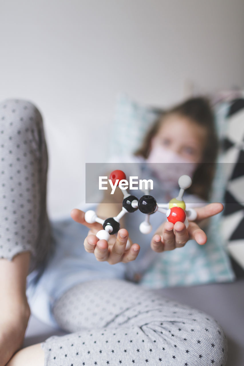 Portrait of girl holding toys on bed