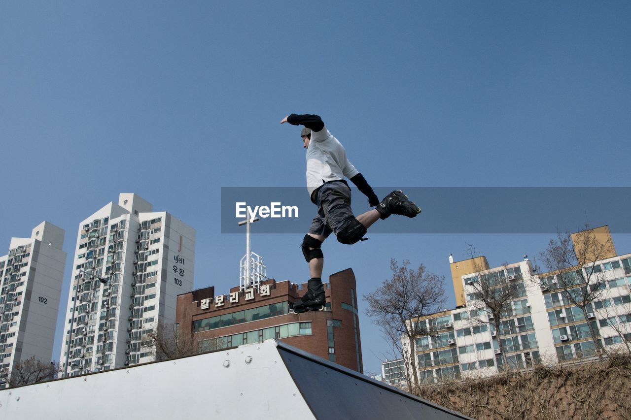 Low angle view of man jumping against clear sky