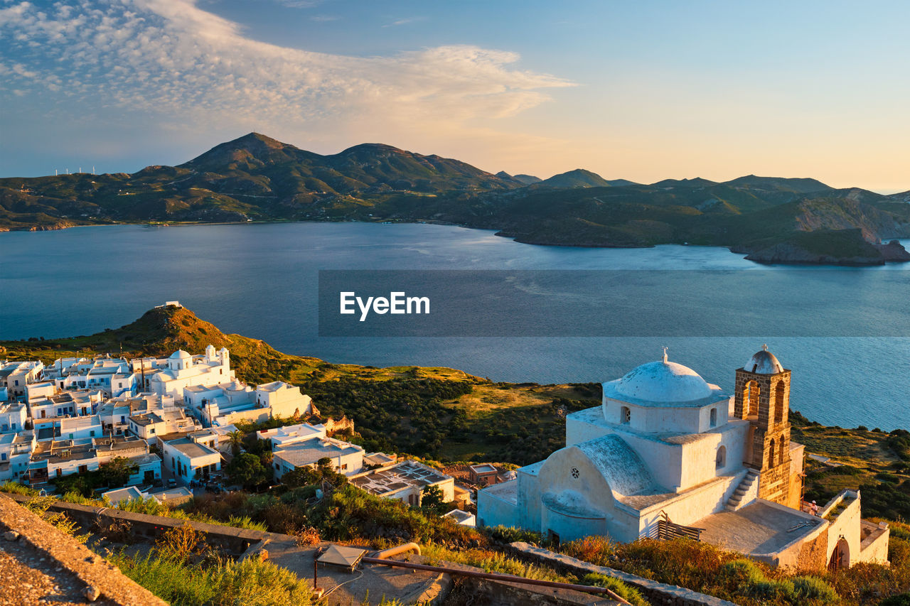 HIGH ANGLE VIEW OF CITY BY BUILDINGS AND MOUNTAINS AGAINST SKY