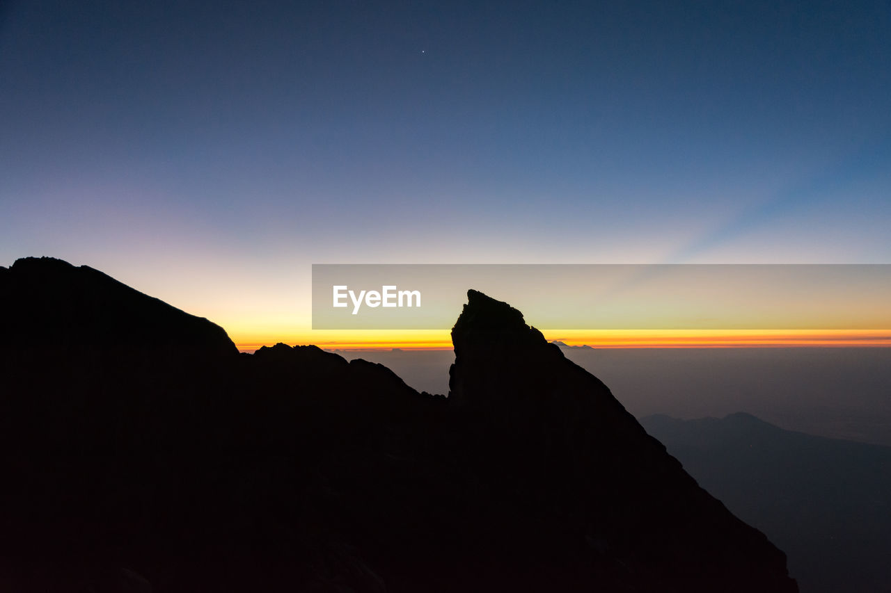 SILHOUETTE OF A ROCK AGAINST SKY DURING SUNSET