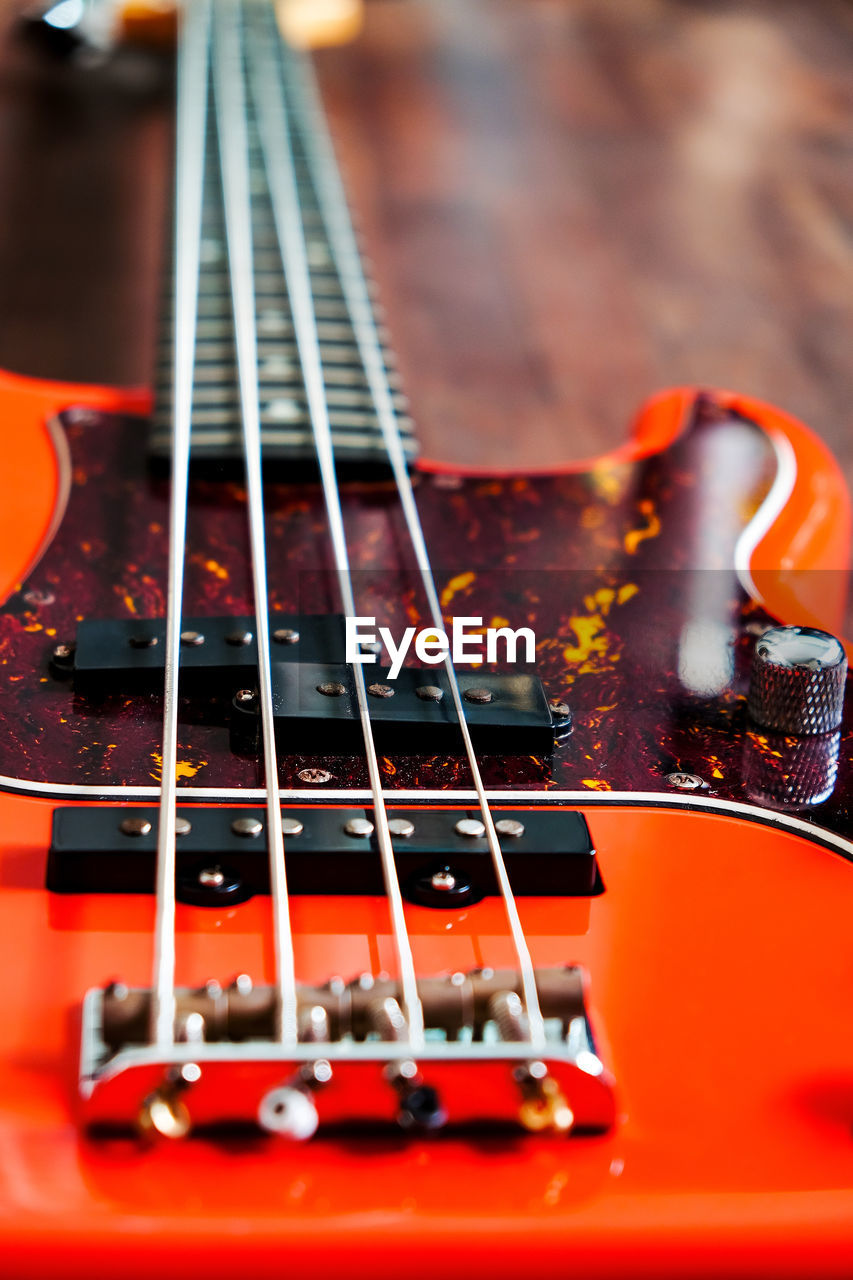 Orange electric bass guitar on wood background with copy space