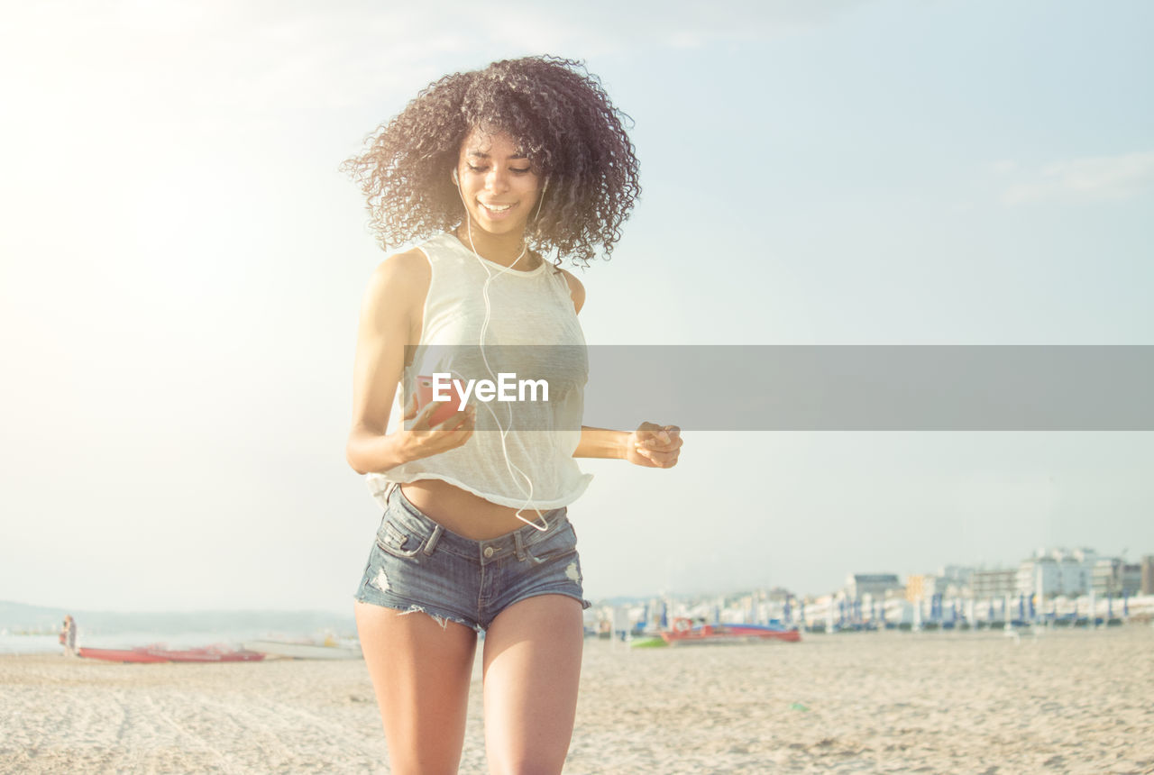 Young woman using mobile phone against sky