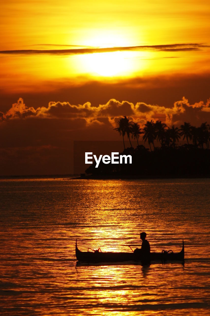 Silhouette man sitting on boat against sky during sunset