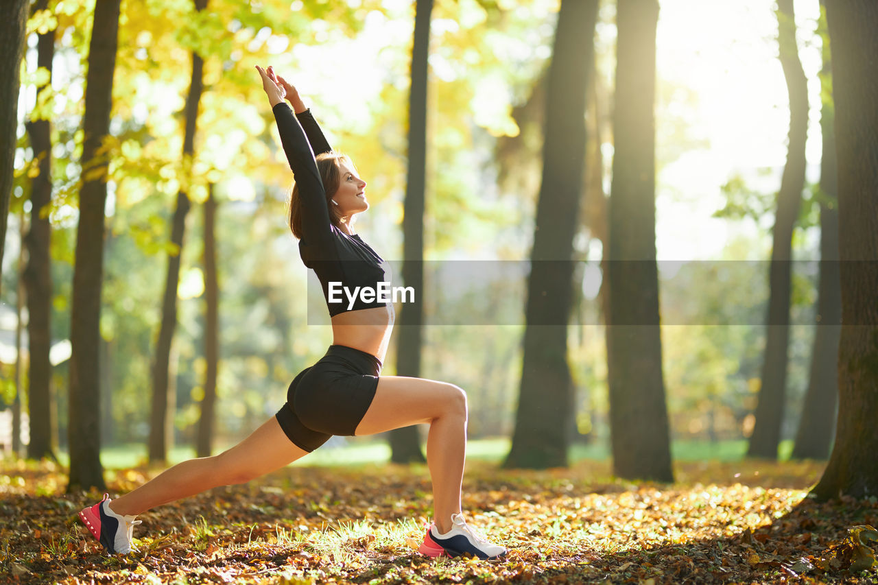 WOMAN WITH ARMS OUTSTRETCHED IN FOREST