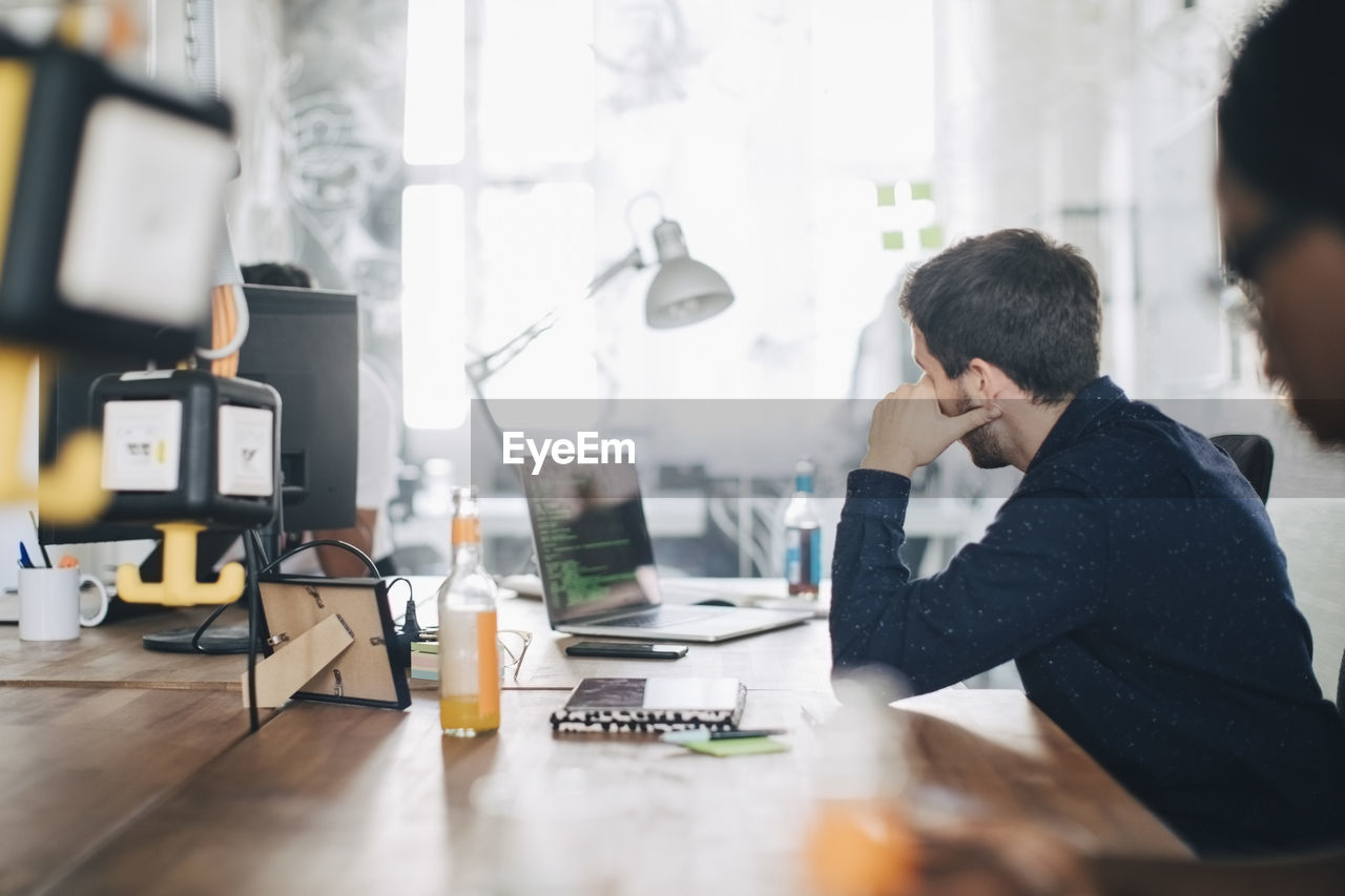 Male computer programmer working at desk in creative office