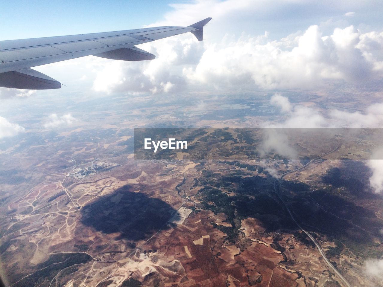 CROPPED IMAGE OF AIRPLANE WING OVER LANDSCAPE