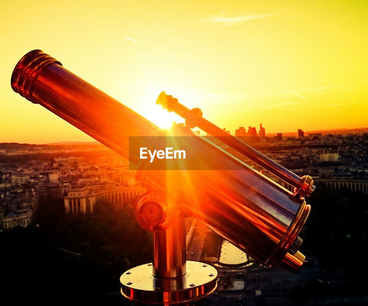 Close-up of binocular against cityscape during sunset