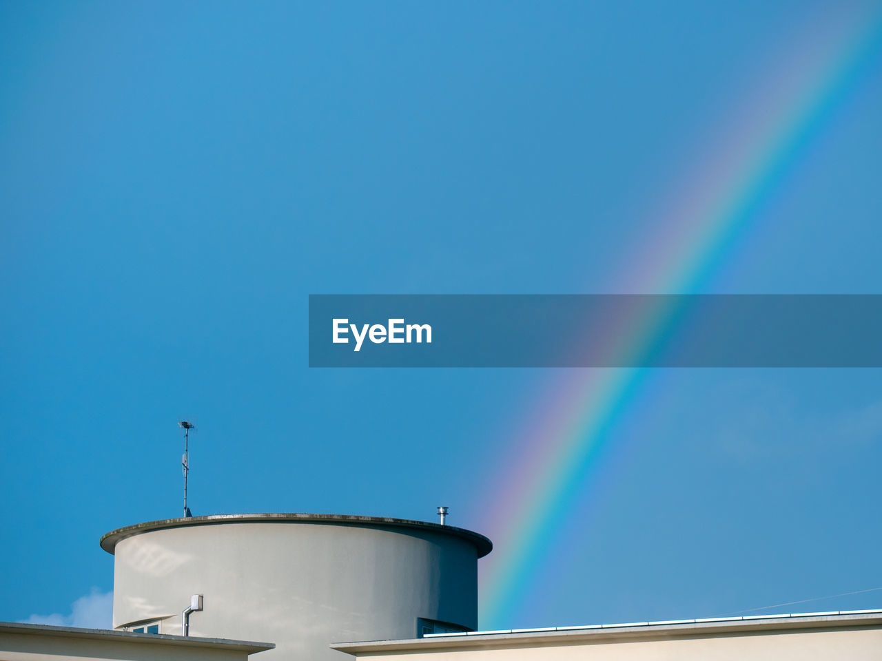 Detail of a rainbow seen above the roof of a building.