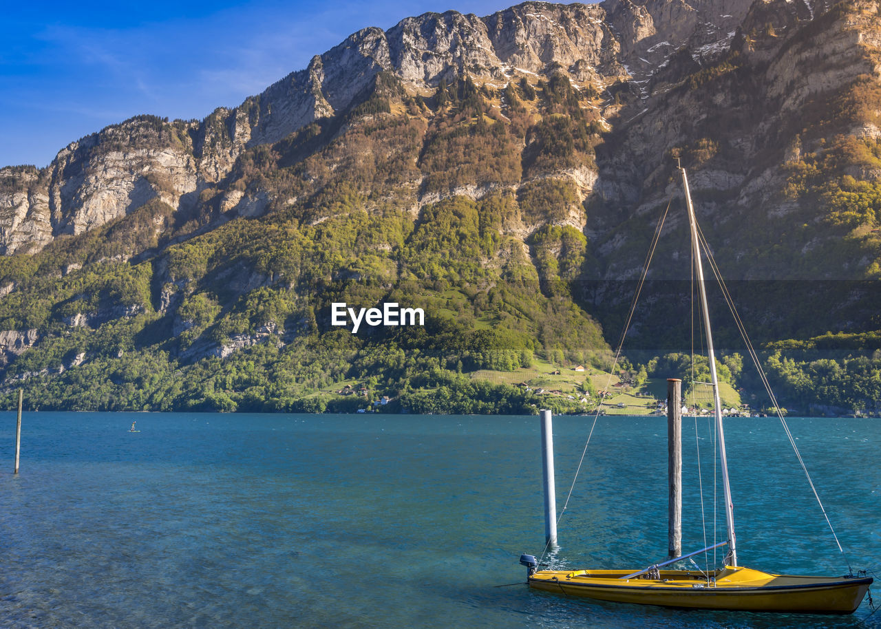 Boat sailing on sea by mountain against sky