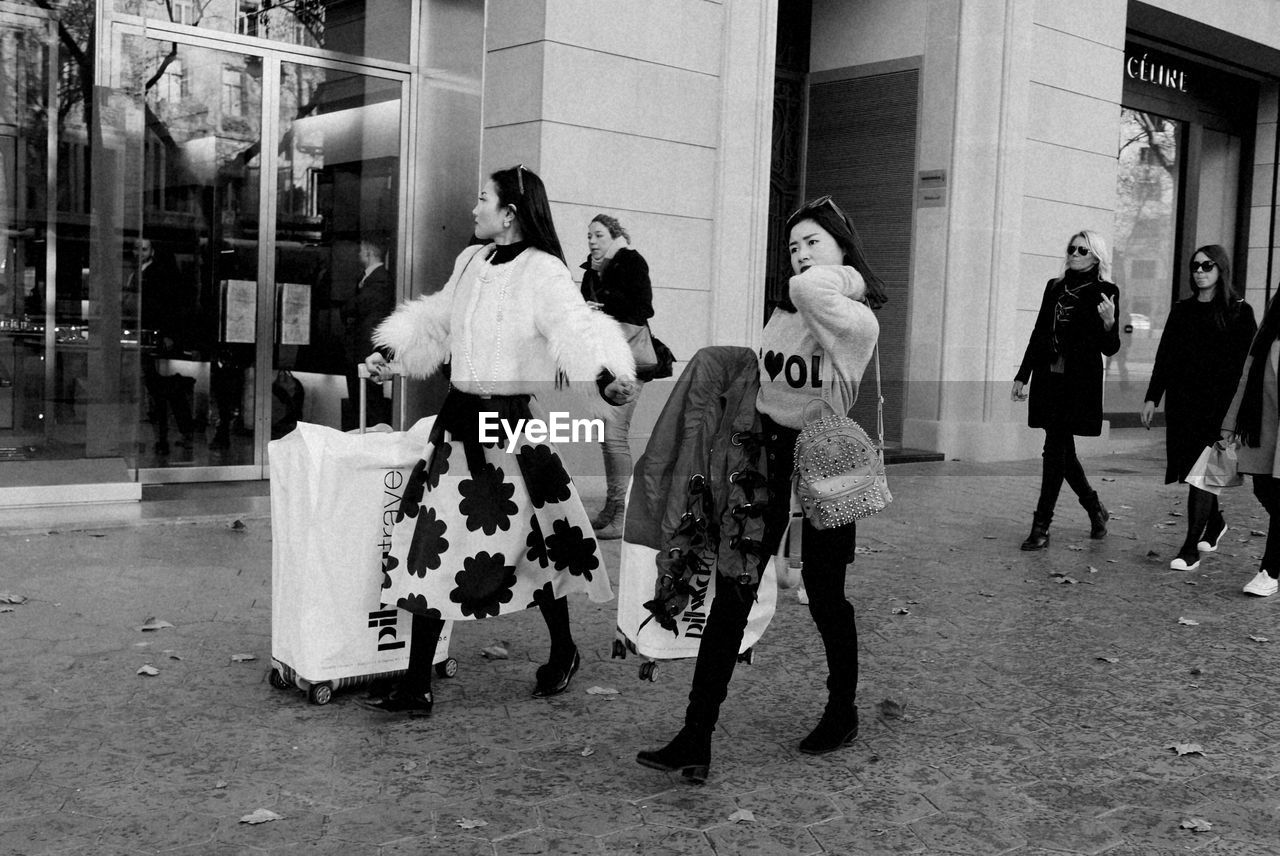 GROUP OF PEOPLE WALKING IN FRONT OF BUILDING