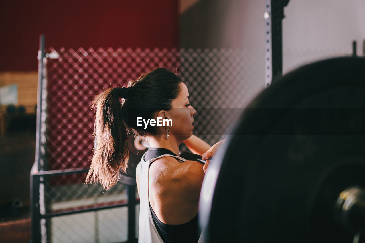 Female athlete exercising with barbell in gym