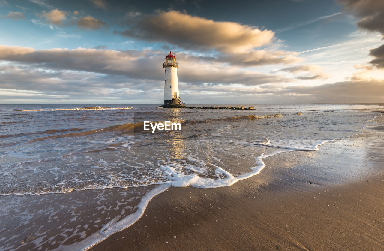 Lighthouse by sea against sky