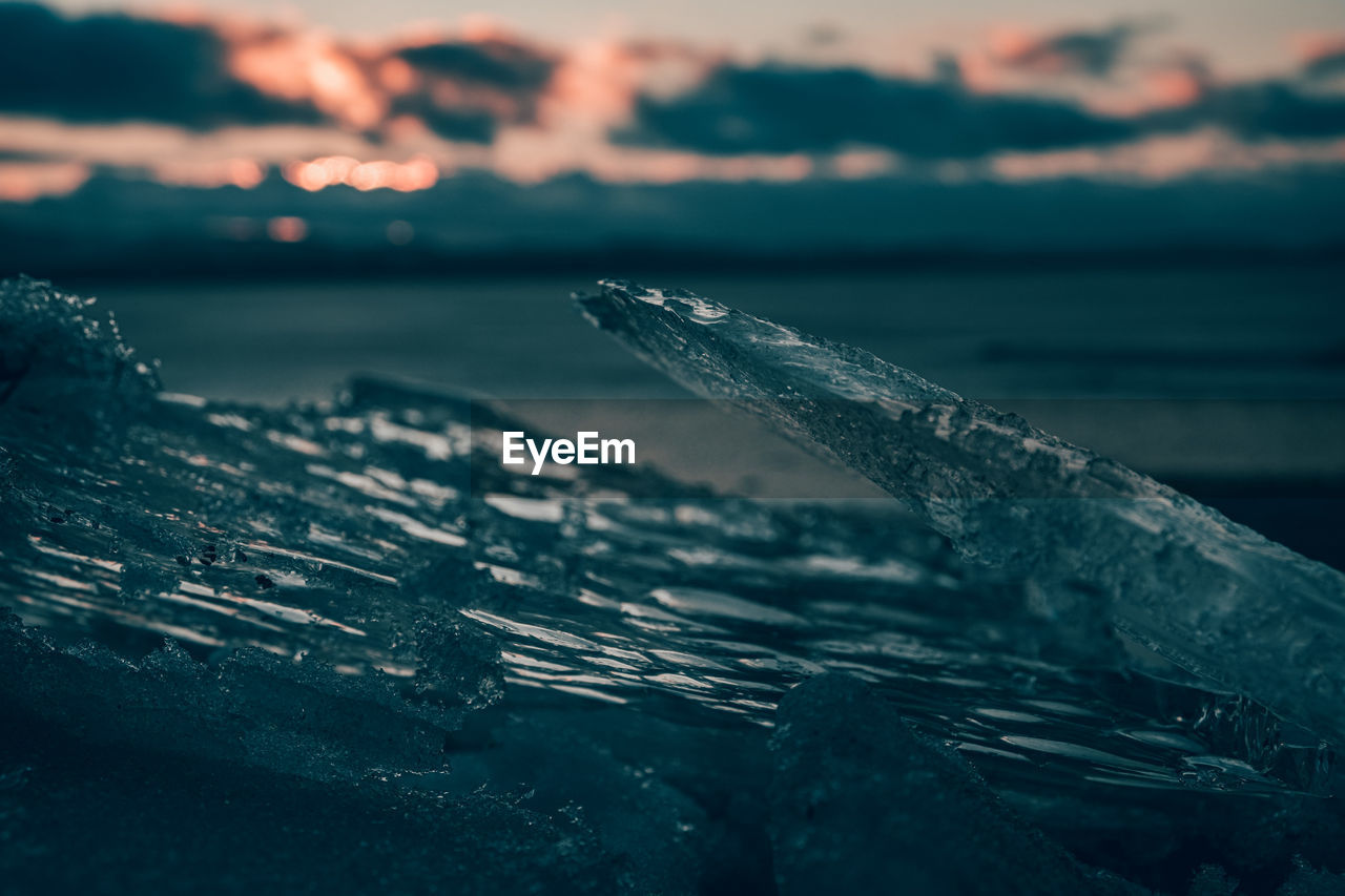 Close-up of frozen water in sea during sunset