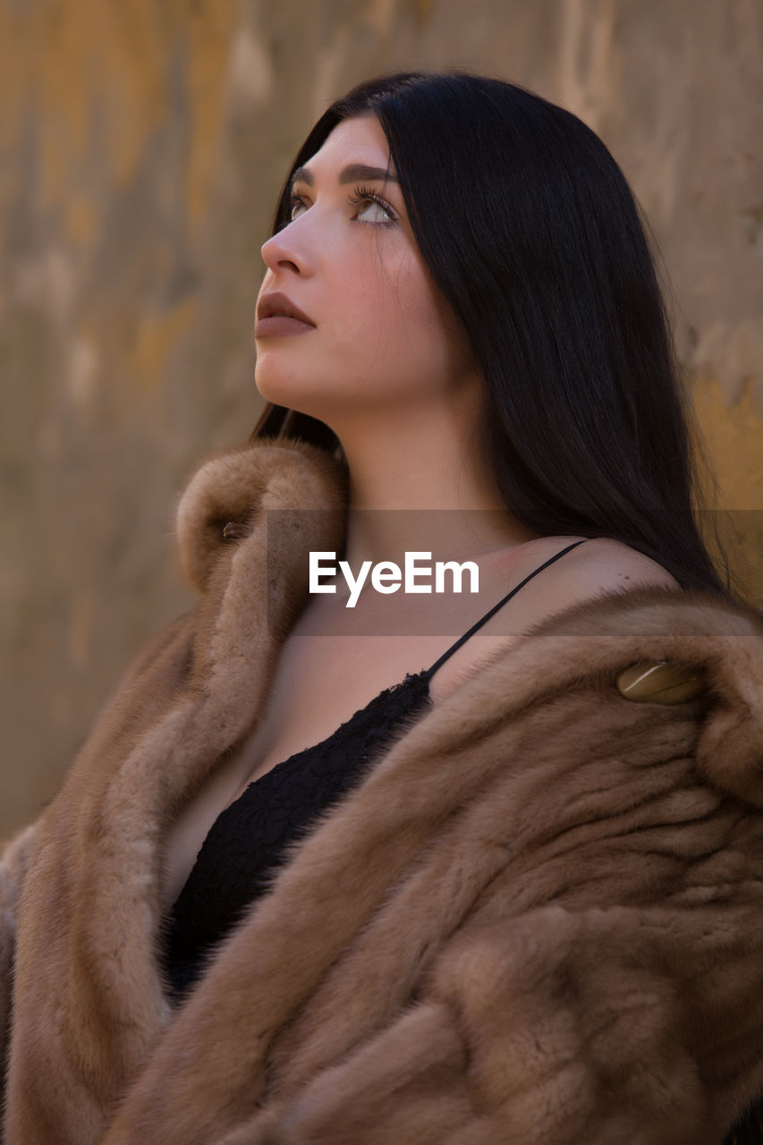 SIDE VIEW OF WOMAN LOOKING AWAY OUTDOORS