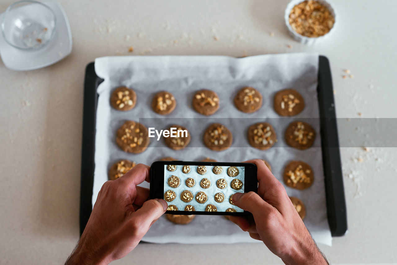 Overhead view of a young man taking a photo of his home-made cookies