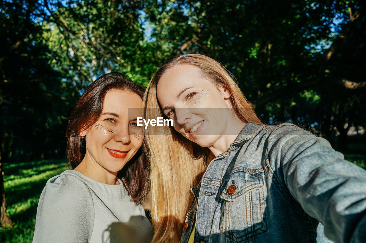 portrait of young woman standing against trees