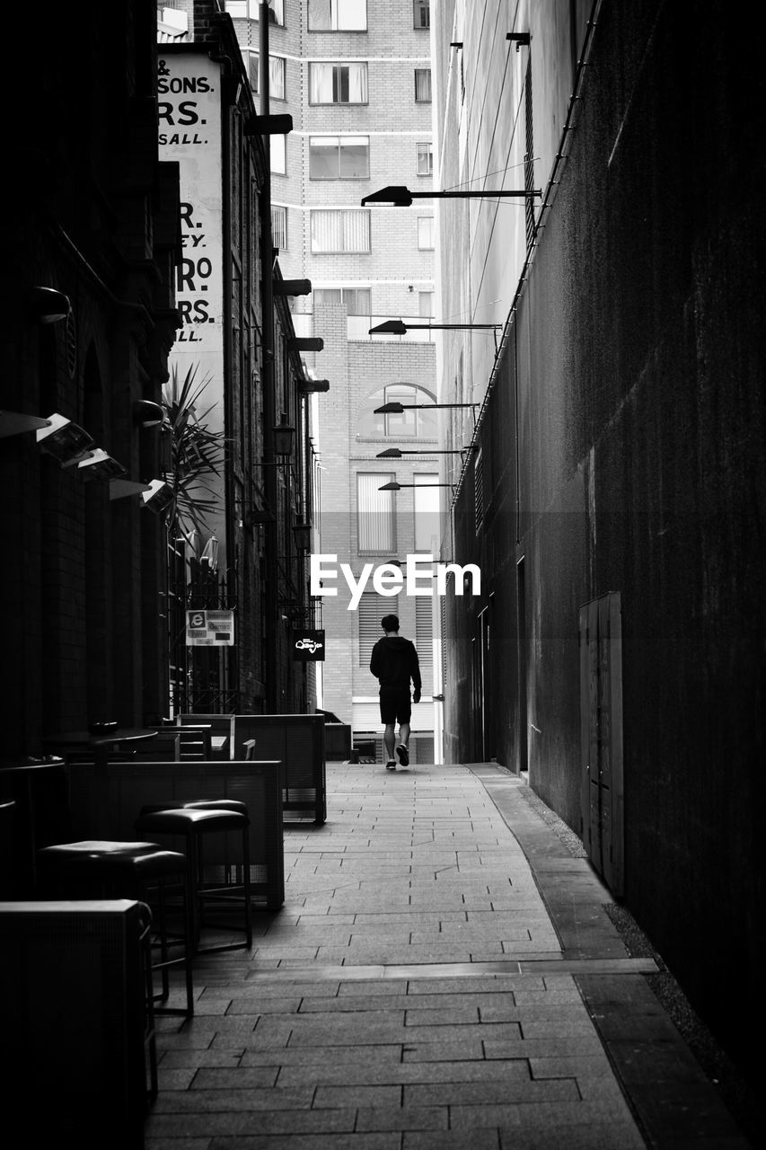 Rear view of man walking in alley