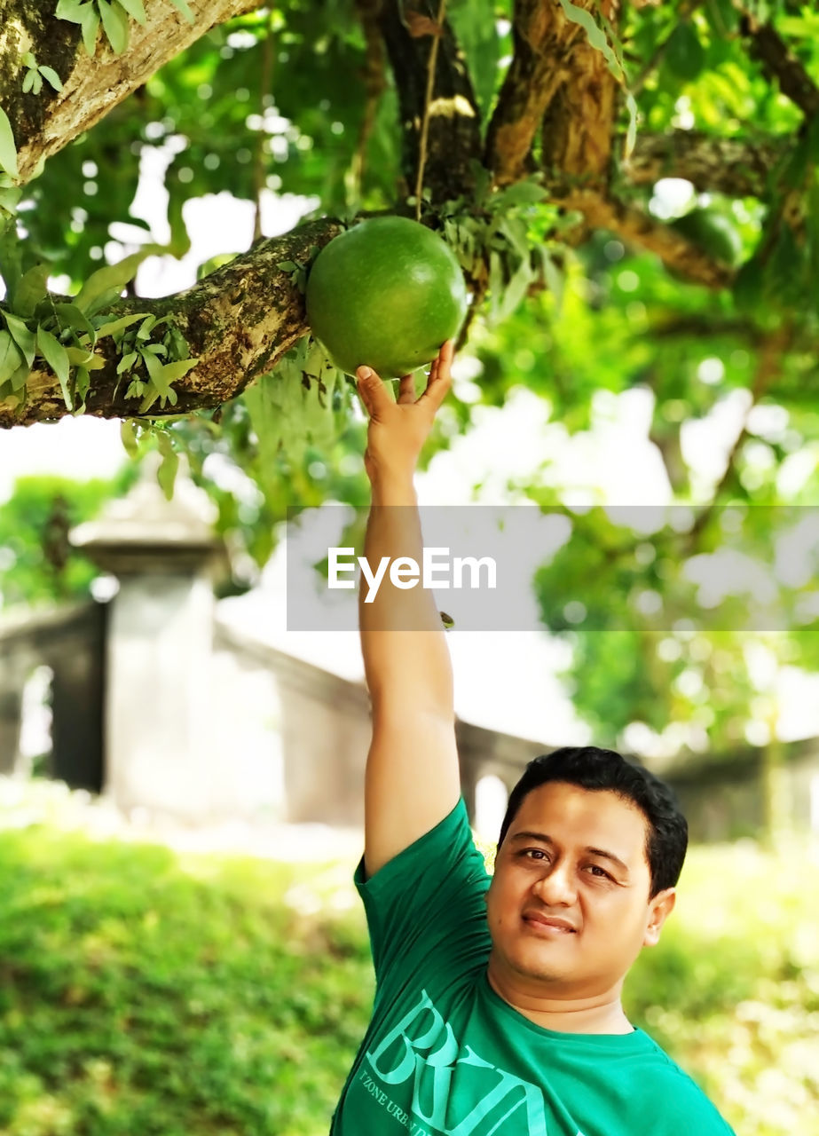 PORTRAIT OF BOY HOLDING APPLE AGAINST TREES