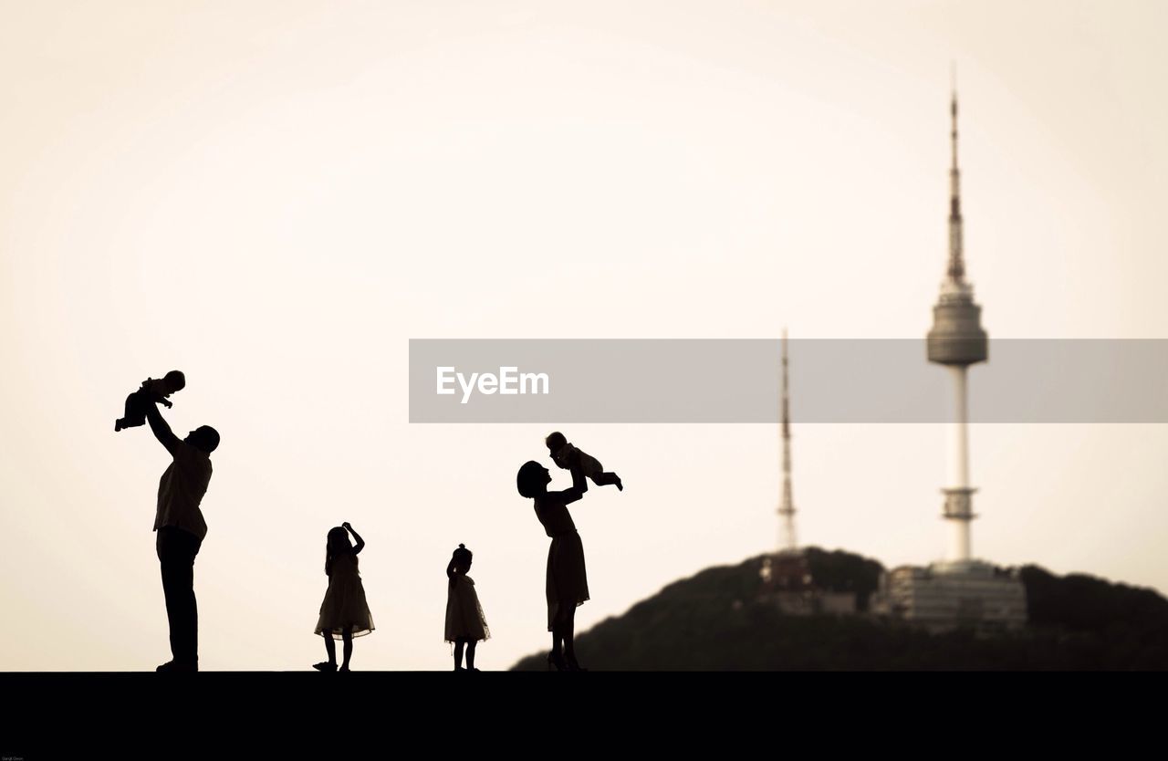 View of silhouette couple with kids over clear sky