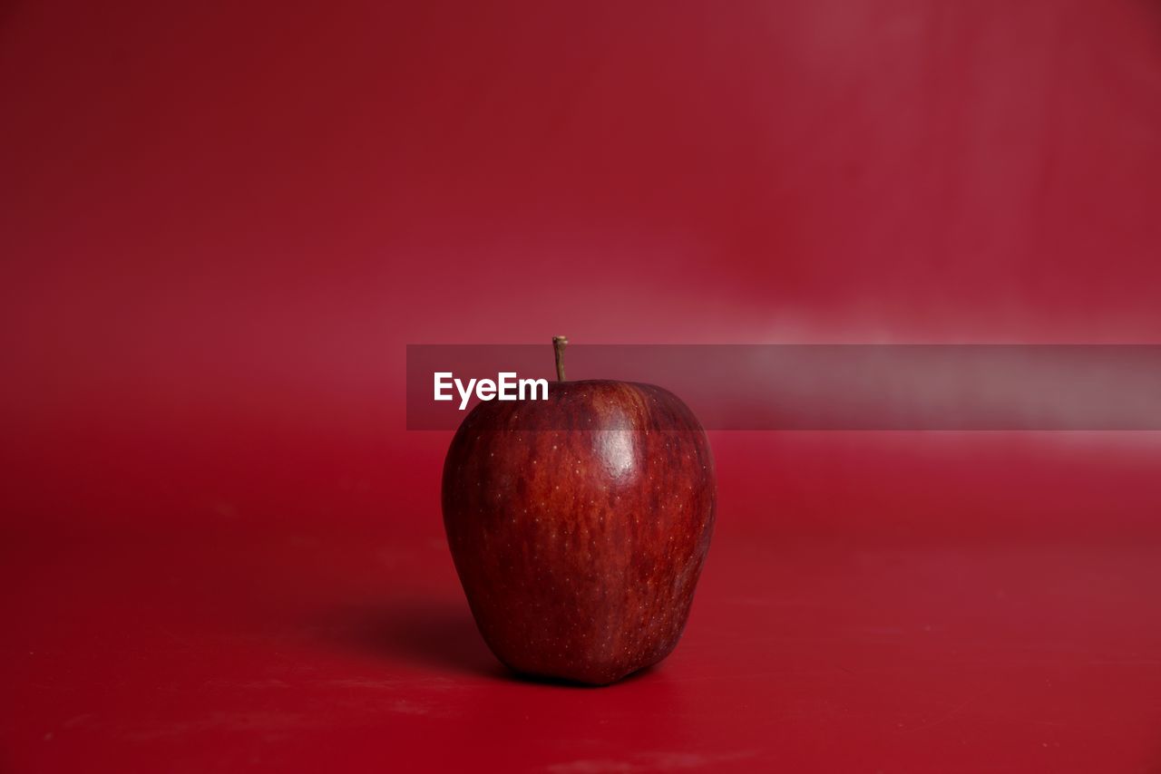 Close-up of apple against red background