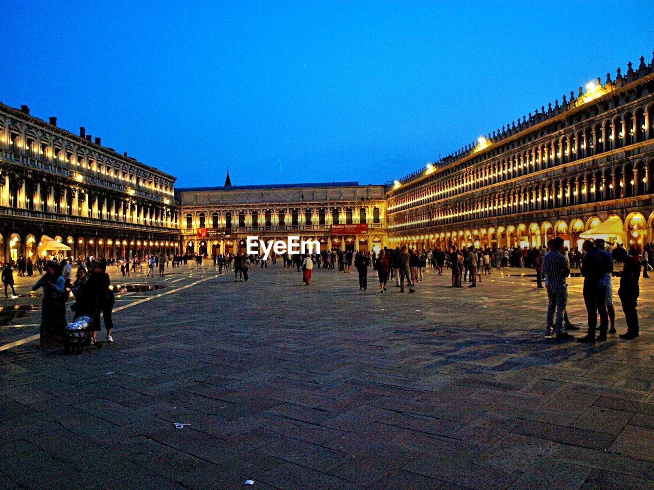 People walking in front of illuminated built structure